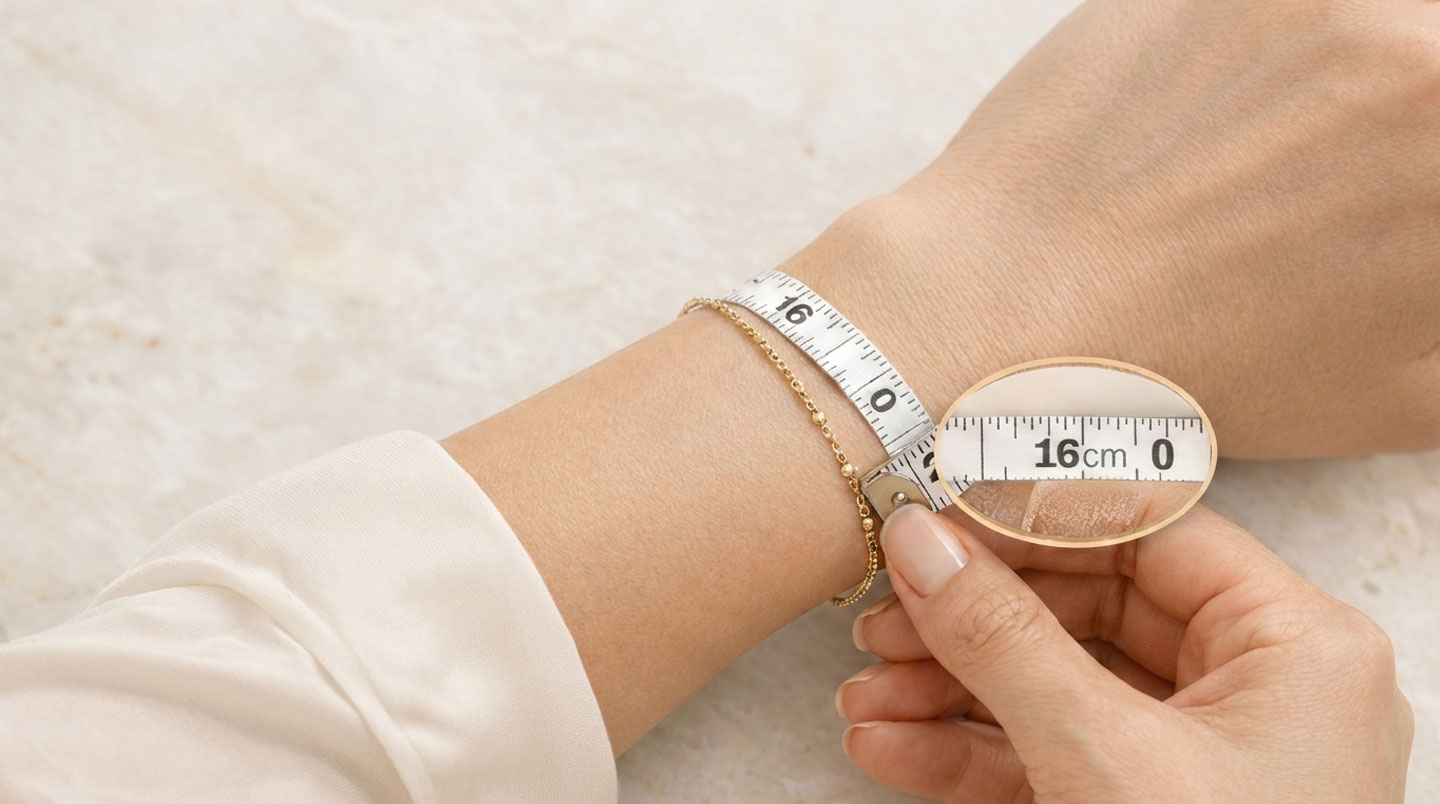 Mains féminines mesurant un poignet avec un mètre ruban de couturière en centimètres, bracelet jonc en or posé sur surface blanche à proximité